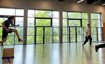 Junger Erwachsener springt in Turnhalle über einen Kasten